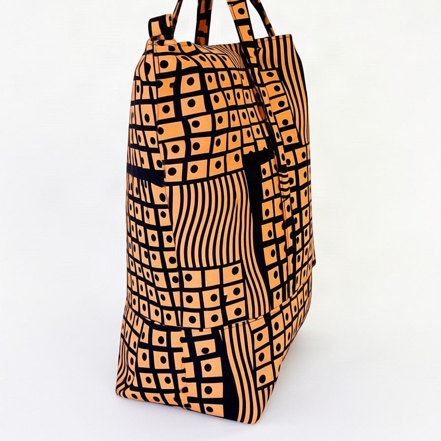 Vista de perfil del bolso tote nil de tela africana con estampdo geomètrico color salmón.