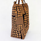 Vista de perfil del bolso tote nil de tela africana con estampdo geomètrico color salmón.